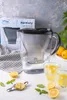 A water filter pitcher and two glasses of lemon water are arranged on a white surface, with lemons and mint leaves scattered around. Náhľad obrázku produktu