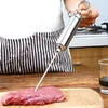 A person is using a stainless steel meat injector to inject marinade into a piece of raw meat on a wooden cutting board. Voir les images du produit