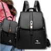 Two black leather backpacks are shown, one in the foreground and one slightly behind and to the left. A person's shoulder and arm are visible on the left side of the image, wearing a pink top. Voir les images du produit