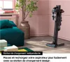 A vacuum cleaner is shown on its charging station in a stylish, modern living room setting with pink walls and a teal sofa. Náhled obrázku produktu