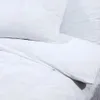A close-up view of white bedding, including a pillow and a duvet cover. Produktbild-Vorschau