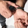 A close-up shot of a person fastening a bracelet on their wrist. Anteprima dell’immagine prodotto