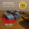 A stack of folded handkerchiefs tied with a ribbon, placed on a wooden surface next to a notebook and pen, with glasses in the background. Produktbild-Vorschau