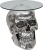A silver skull-shaped side table with a glass top, presented against a white background. Podgląd zdjęcia produktu