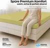A person sitting on a bed with a fitted sheet. Produktbild-Vorschau