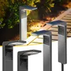 Several solar-powered pathway lights are displayed in a garden setting with a pathway. Náhľad obrázku produktu