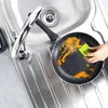 A person is cleaning a frying pan in a kitchen sink. Náhľad obrázku produktu