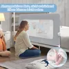 A woman is sitting on the floor next to a bed with a baby safety guard. The guard has a mesh window through which a baby can be seen. There is text overlay on the top of the image. A zoomed in image of baby feet is in the bottom right corner. Voir les images du produit