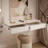 A white floating vanity desk with gold trim, open drawers, and makeup accessories. Náhled obrázku produktu