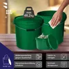 Two green buckets are shown on a wooden surface, with a hand cleaning one of them. A small container of garlic is in front of the buckets. Anteprima dell’immagine prodotto