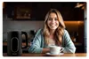 A woman is sitting at a table with a cup of coffee and a kettle. Náhled obrázku produktu