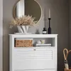 A white shoe cabinet with louvered doors and a shelf above, holding decor items like a vase with dried flowers, books, and a candle holder. Anteprima dell’immagine prodotto