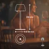 A couple is sitting at a table in a dimly lit restaurant, with a diagram of a table lamp overlaid on the image. Anteprima dell’immagine prodotto