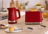 A red Bosch kettle and toaster are on a wooden countertop, with breakfast items in the foreground. Voir les images du produit