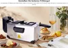 A deep fryer is shown on a table with food, lemons, a glass of wine, and a book. Produktbild-Vorschau