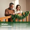 A couple decorating a staircase railing with a green garland. Anteprima dell’immagine prodotto
