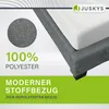 A close-up view of a grey upholstered bed frame with a white mattress, featuring marketing text and a brand logo. Náhled obrázku produktu