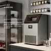 A Klarstein ice maker is shown on a countertop next to a refrigerator, with jars of spices on a shelf above. Produktbild-Vorschau