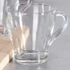 A clear glass mug sits on a countertop next to a wooden cutting board. Anteprima dell’immagine prodotto