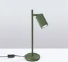 A green desk lamp on a white surface against a gradient background. Voir les images du produit