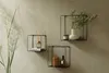 Three black metal cube shelves are mounted on a light gray wall, each displaying decorative items. A tall, feathery plant is positioned to the left of the shelves. Anteprima dell’immagine prodotto