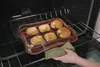 A hand is placing a baking tray with pastries into an oven. Podgląd zdjęcia produktu