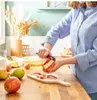 A person is peeling an apple in a kitchen setting. Produktbild-Vorschau