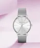 A silver Armani Exchange watch with a mesh band is displayed against a soft pink and white background. Voir les images du produit