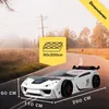 A white race car bed is shown on a road with a scenic background. Produktbild-Vorschau