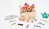 A collection of wooden toy gardening tools and flowers arranged on a white background. Anteprima dell’immagine prodotto