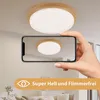 A ceiling light is shown mounted on a ceiling, with a smartphone held up to capture its reflection. Produktbild-Vorschau