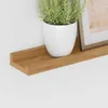 A close-up shot of a wooden shelf with a potted plant and a framed picture. Produktbild-Vorschau