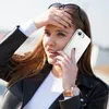 A young woman is holding a clear phone case to her ear while talking on the phone, with her hand on her forehead. Náhľad obrázku produktu