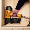 A hand is holding a Bostitch nail gun, aimed at wooden boards. Produktbild-Vorschau