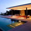 A modern outdoor living space with a swimming pool and covered patio area at dusk. Produktbild-Vorschau