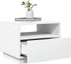 A white bedside table with one drawer partially open, a shelf, and books with a vase of greenery on top. Náhled obrázku produktu