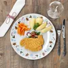 A festive Christmas-themed plate of food, including a breaded cutlet, potatoes, and carrots, set on a wooden table with a napkin and cutlery. Náhled obrázku produktu