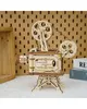 A wooden model of a film projector is displayed on a table with a pegboard wall in the background. Produktbild-Vorschau