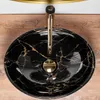 A top-down view of a black marble sink with gold veining, featuring a gold faucet. Náhľad obrázku produktu
