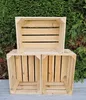 Three wooden crates are stacked in front of a green hedge. Produktbild-Vorschau