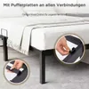 A close-up view of a black metal bed frame with white bedding, highlighting assembly details. Voir les images du produit