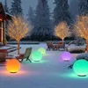 A snowy garden scene at dusk, with illuminated spherical lamps in various colors scattered across the snow. Trees decorated with fairy lights are visible in the background, along with outdoor furniture. Anteprima dell’immagine prodotto