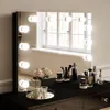 A vanity mirror with lights and makeup accessories on a black vanity. Produktbild-Vorschau