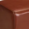 A close-up view of the corner of a brown leather ottoman or bench. Voir les images du produit
