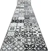 A long hallway runner rug with a patchwork tile pattern in gray and black. Produktbild-Vorschau