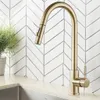 A gold kitchen faucet is shown in front of a white herringbone tile backsplash. Produktbild-Vorschau