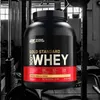 A large tub of protein powder in a gym setting. Produktbild-Vorschau