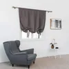 A gray armchair sits next to a window with gray tie-up curtains, a small white side table with a vase and a cup, and a framed abstract painting on the wall. Náhled obrázku produktu