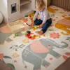 A toddler plays with toy food on a colorful play mat with elephant and floral designs, next to a toy kitchen. Anteprima dell’immagine prodotto