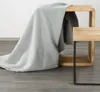 A grey blanket draped over a wooden and metal side table. Náhľad obrázku produktu